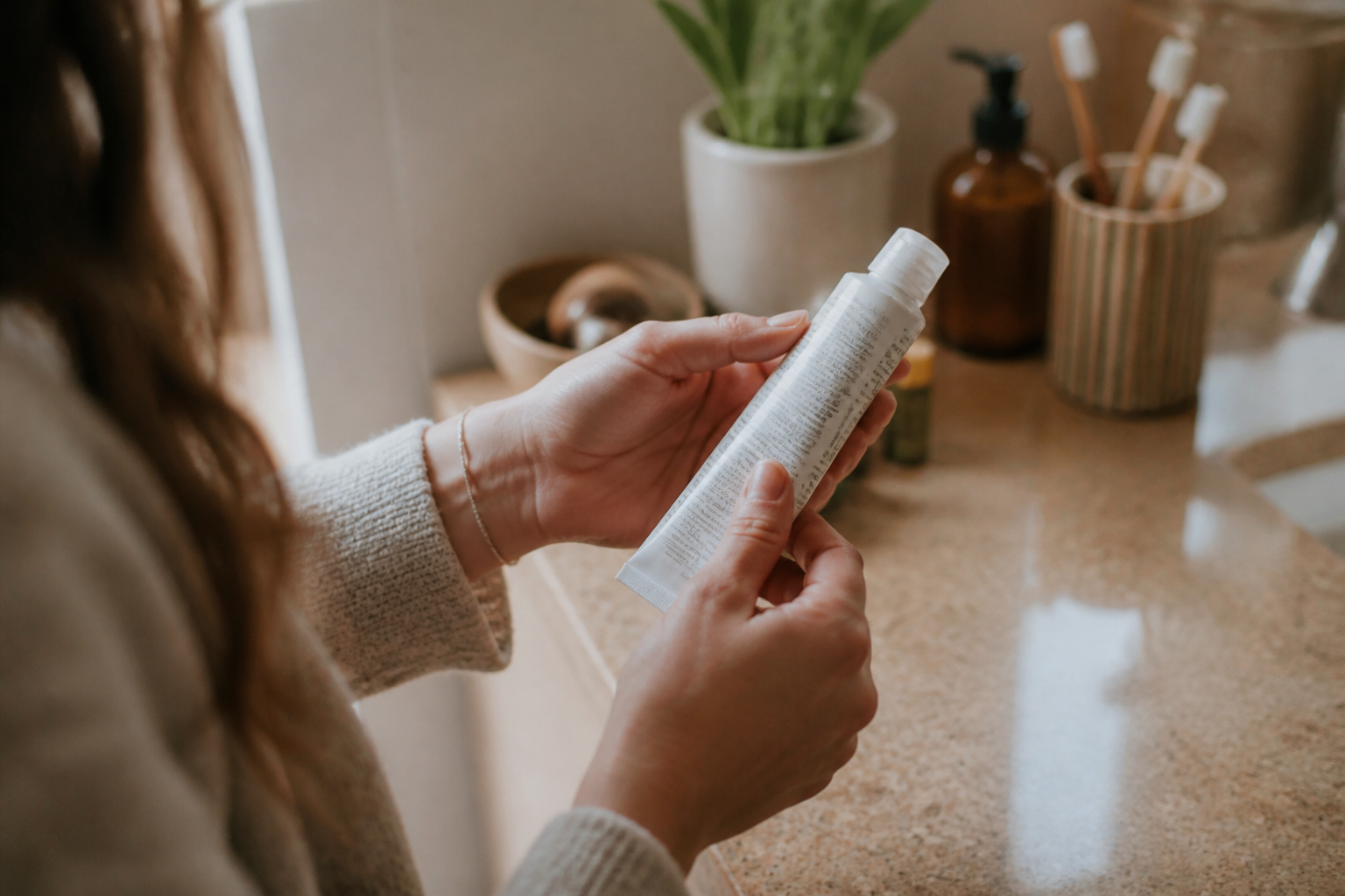 Hands holding a toothpaste tube, reading the small print on the back